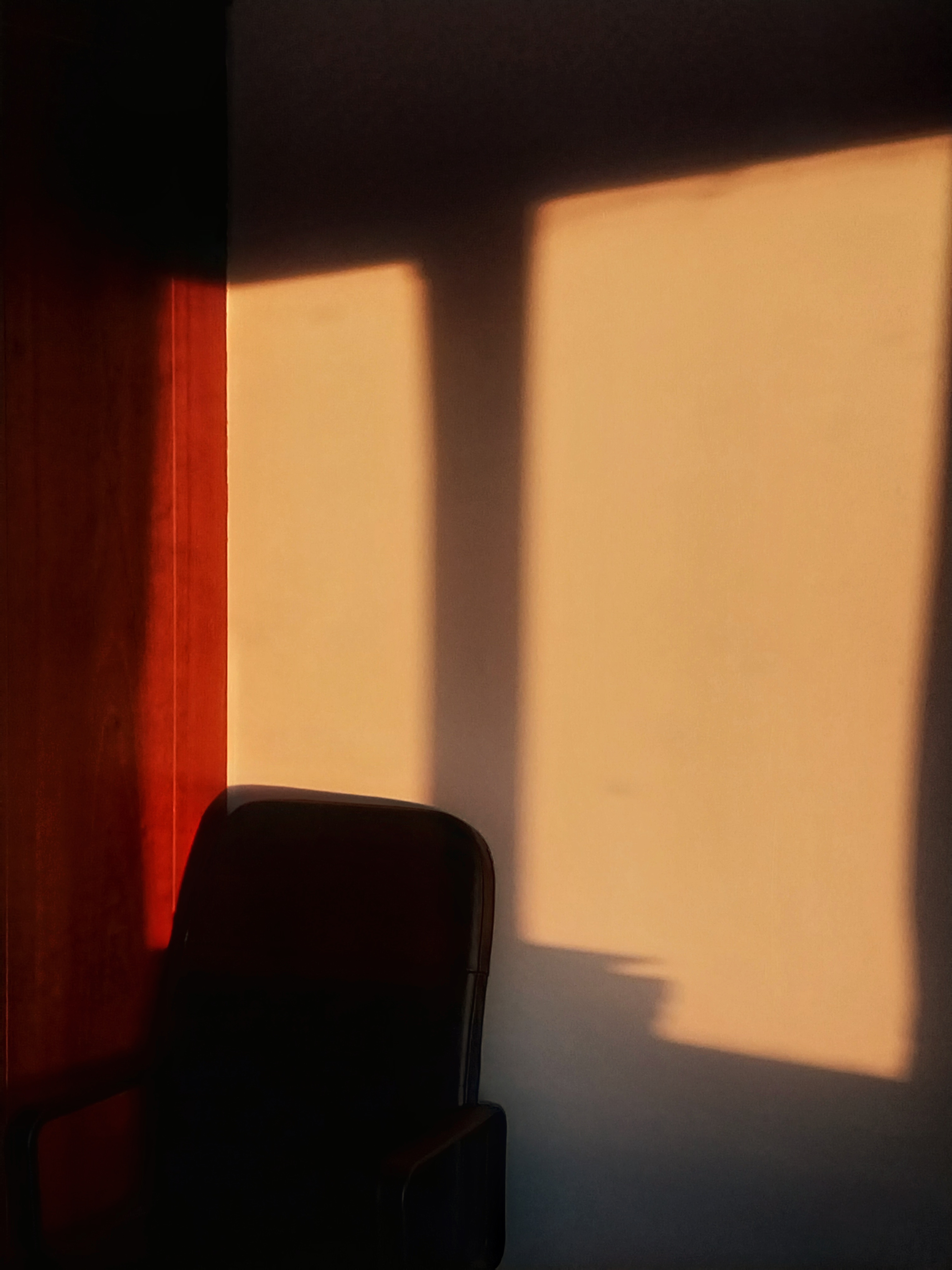 A sunrise projected through a window onto a wall with a chair.